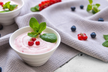 Bowl with tasty yogurt and berries on table