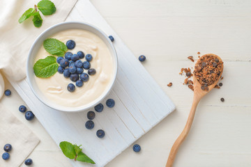 Bowl with tasty yogurt, granola and berries on table