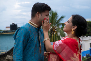 A brunette Indian Bengali romantic couple in traditional wear enjoying themselves standing on the...