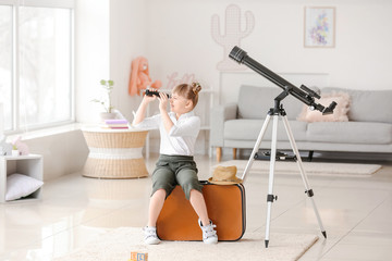 Cute little traveler with spyglass at home