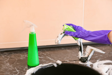 Woman cleaning sink in kitchen