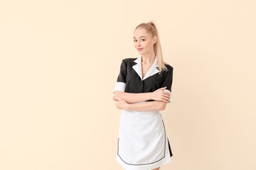 Beautiful young chambermaid on light background