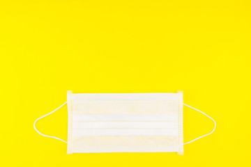 Surgical Face Mask isolated on yellow background. Coronavirus Concept. Medical Face Mask For Stopping The Spread of Virus. Surgical mask with rubber ear straps. surgical mask to cover the mouth nose.