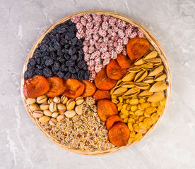 Wooden plate with a set of nuts, apricots, raisins, sesame