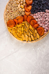 Wooden plate with a set of nuts, apricots, raisins, sesame