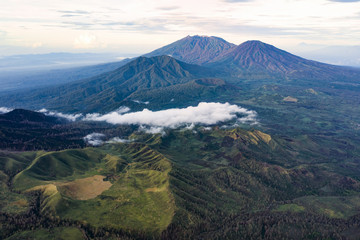 Fototapeta premium Stunning aerial view of a beautiful mountain range surrounded by clouds during sunrise. Ijen Volcano complex. The Ijen volcano complex is a group of composite volcanoes located in East Java, Indonesia