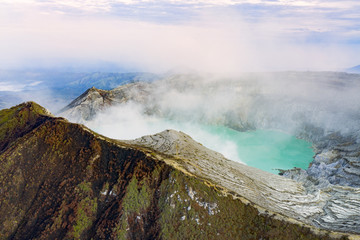 Fototapeta na wymiar View from above, stunning view of the Ijen volcano with the turquoise-coloured acidic crater lake. The Ijen volcano complex is a group of composite volcanoes located in East Java, Indonesia.