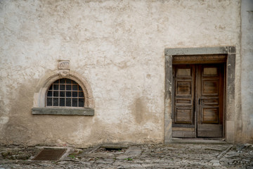 Fototapeta na wymiar Old Crooked Wooden Door In Stone Wall