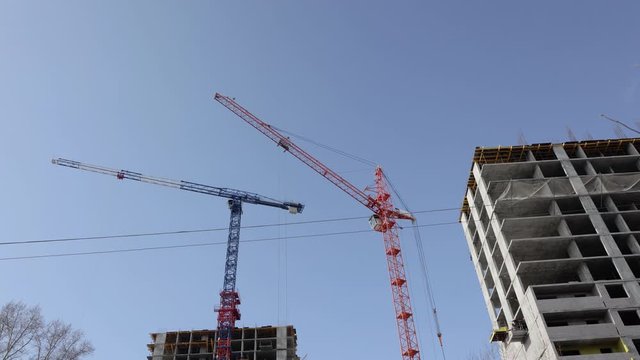 4K Time Lapse Construction cranes move cargo and work on the construction of residential multi-storey buildings
