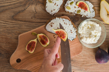 woman makes sandwiches with curd cheese and figs