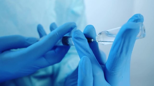 Drug addiction recovery. Narcotic rehab. Doctor hands in gloves filling syringe from ampoule.