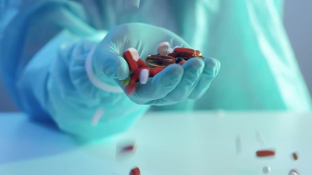 Coronavirus disease. Prescription drug. Pills scattering into doctor hand in protective glove.