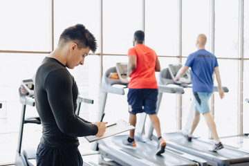 Fototapeta premium young guy trainer takes notes in the gym. personal trainer for sports.