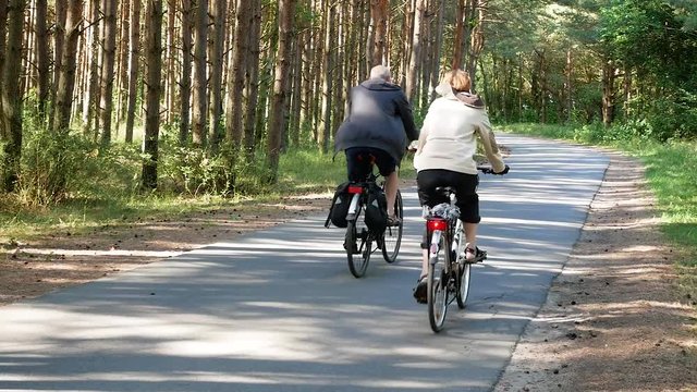 Smiling couple cycling through a forest together, close up