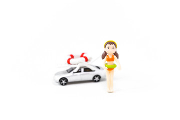 Fototapeta premium Gril with orange bikini doll over blurred car with summer object on the roof isolate on white background, summer concept, summer holiday