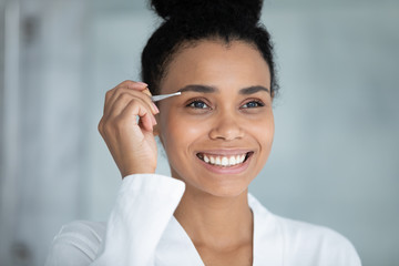 African beautiful woman with white perfect teeth charming wide smile holding metal tweezers...