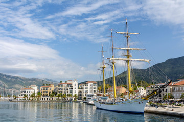 Fototapeta na wymiar Montenegro Tivat. Embankment with a view of the mountains, pier and sailboat
