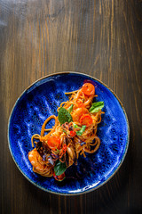 Italian spaghetti pasta marinara with Clams, Prawns, Mussels, tomato, Seafood Cocktail in blue plate on wooden table background