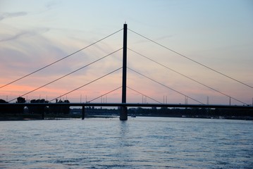 View of the cable-stayed Oberkasseler Brucke  bridge over the Rhine in Dusseldorf, Germany with a perfect purple sunset