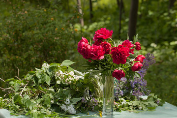 Red peonies in a glass vase on a spring background