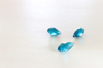 Beautiful blue crystal drops beads over white wooden background