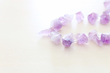 Fototapeta na wymiar Purple gemstones beads on white wooden background