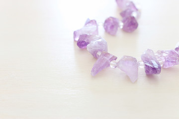 Purple gemstones beads on white wooden background