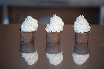 Line of three chocolate cupcakes or cup cakes with frosting or icing, brown and white. Photographed...