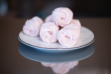 Obraz na płótnie Canvas Homemade pink meringue nest on plate on tainless steel table, reflection on table.