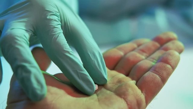 COVID-19 epidemic. Medical treatment. Doctor hand in protective glove giving pill to male patient.