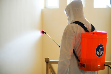 A man in protective equipment disinfects with a spraye in building. Surface treatment due to...