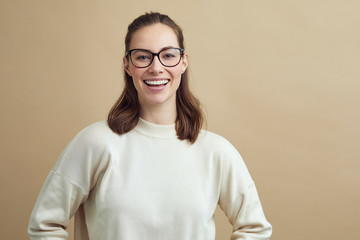 portrait of a young woman with glasses smiling and looking in to the camera - obrazy, fototapety, plakaty