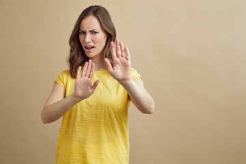 Portrait of young attractive woman holding her hands up infront of the viewer to signal 