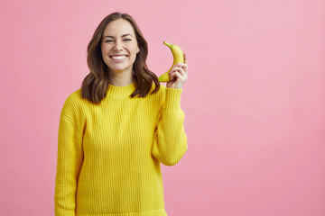 Portrait of pretty girl pretending that the banana is a phone 