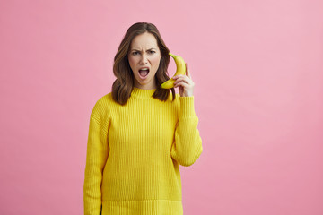 Portrait of angry girl pretending that the banana is a phone 