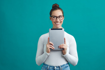 Smart looking student with glasses, smiling and looking to the copy space, while holding a tablet