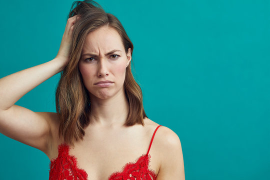 Portrait of girl in red lingeri being confused looking into the camera while standing on a colorful background