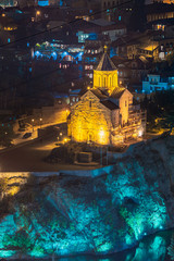 Tbilisi, Georgia. Night Evening Illuminated View Of Metekhi Church And Saint George's Church