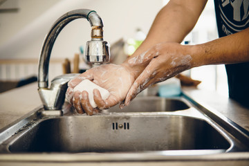 Mature man and woman washing hands in the kitchen