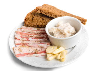 Thin sliced raw salted bacon served with lard, garlic, bread on a plate isolated on white background. Appetizer for borsch. Food.