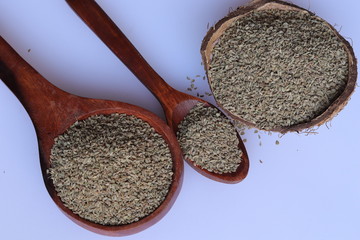 Ajwain seeds in a wooden spoon over white background