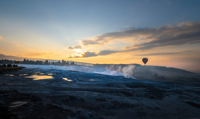 Silhouette of a balloon flying with colourful sunrise sky and cloud at view point of Pamukkale, Turkey.