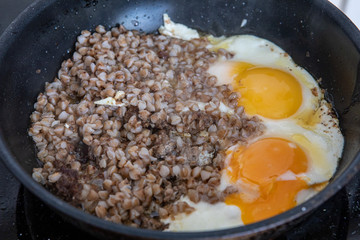 In the pan is cooked buckwheat and two fried eggs.