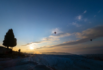 Pamukkale, Denizli, Turkey - December 5th 2019 : Silhouette of balloon flying with colourful sunrise sky and cloud at view point of Pamukkale, Turkey.