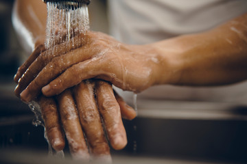 Cropped shot of an unrecognizable man washing his hands at home to prevent spreading of the...