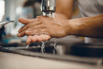 Cropped shot of an unrecognizable man washing his hands at home to prevent spreading of the...