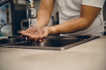 Cropped shot of an unrecognizable man washing his hands at home to prevent spreading of the coronavirus ( Covid-19)