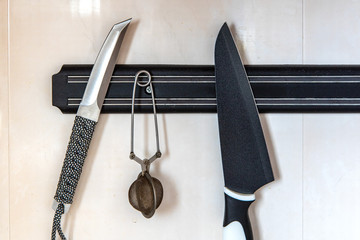 Sharp knives hanging on a magnetic board in the kitchen