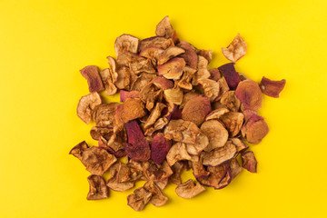 Homemade dried fruit Apple chips scattered on a yellow background. Organic natural healthy food.