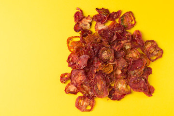 A scattering of sun-dried tomatoes on a beautiful yellow background. Copy space.